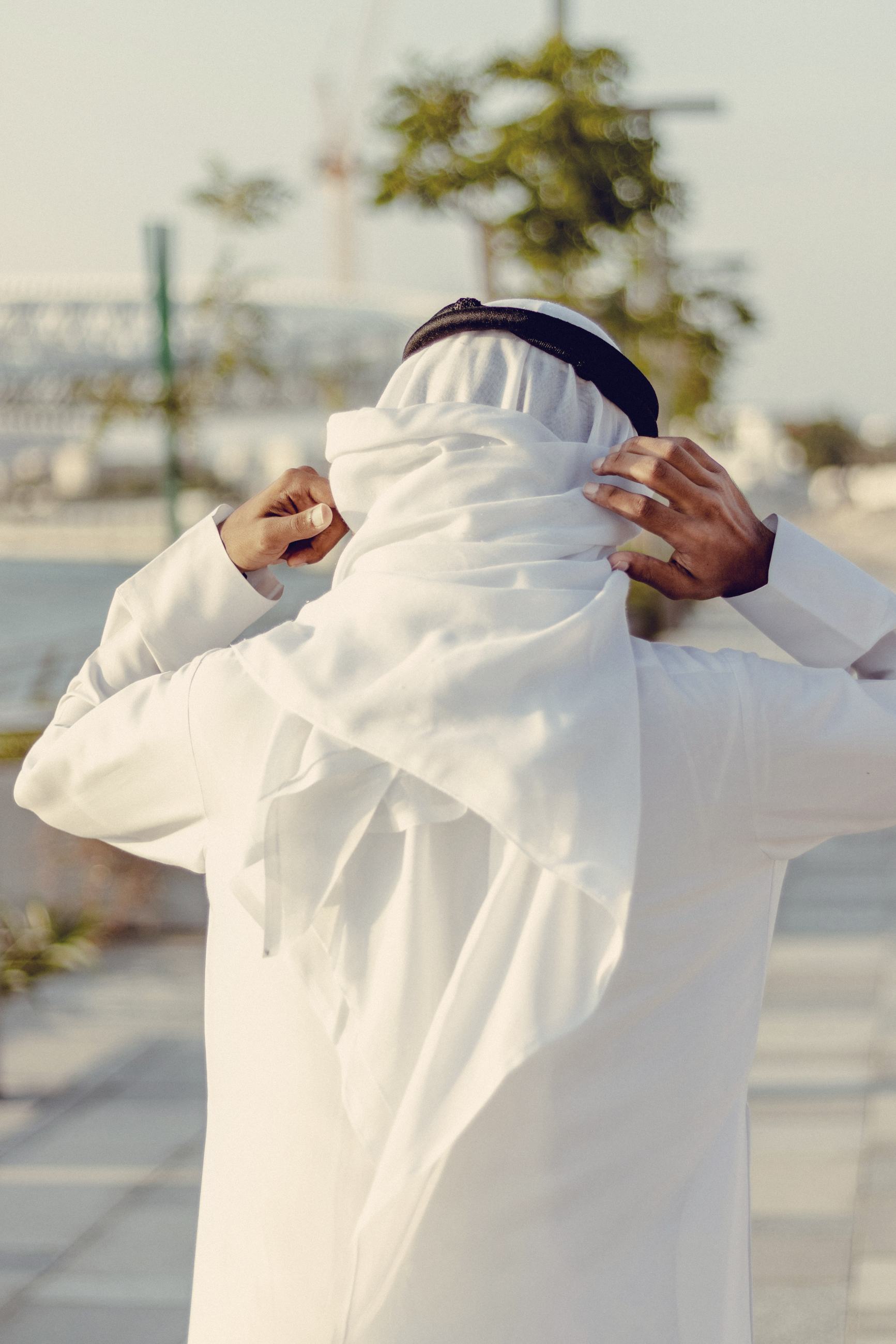 A man adjusting a white ghutra