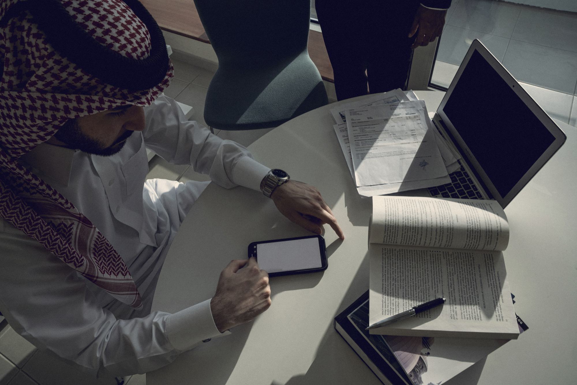 Reviewing reports on a phone and laptop at a meeting table